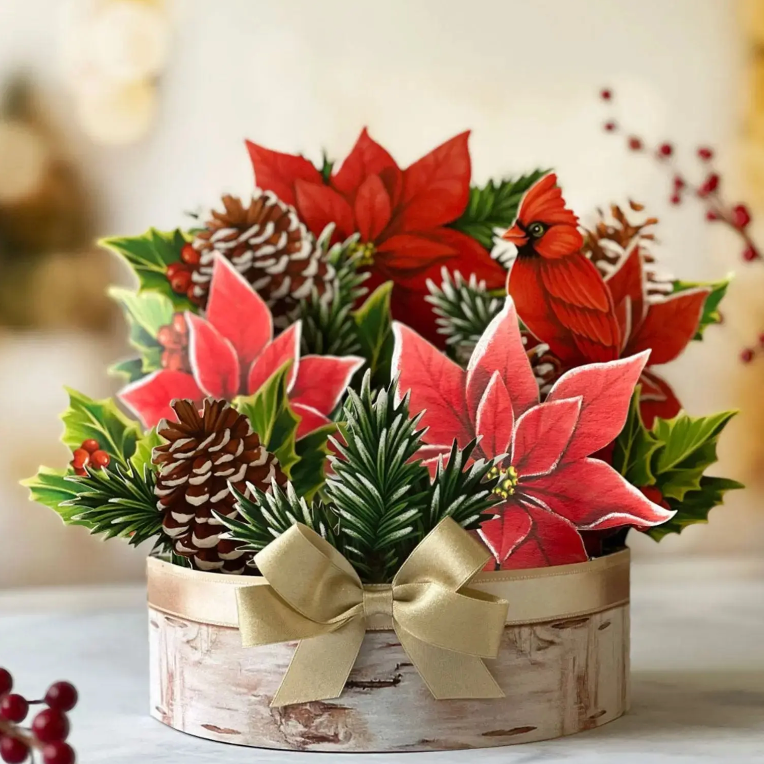 Decorative arrangement with poinsettias, cardinal birds, and pinecones on a blurred background
